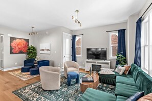 Un salon moderne comprenant un canapé, un fauteuil, une table basse et un téléviseur à écran plat.