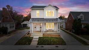 A two-story house with a front porch, a garage, and a driveway. - Spacious 4BR w/ Basement Game Room • Lux Listings (Alexandria)