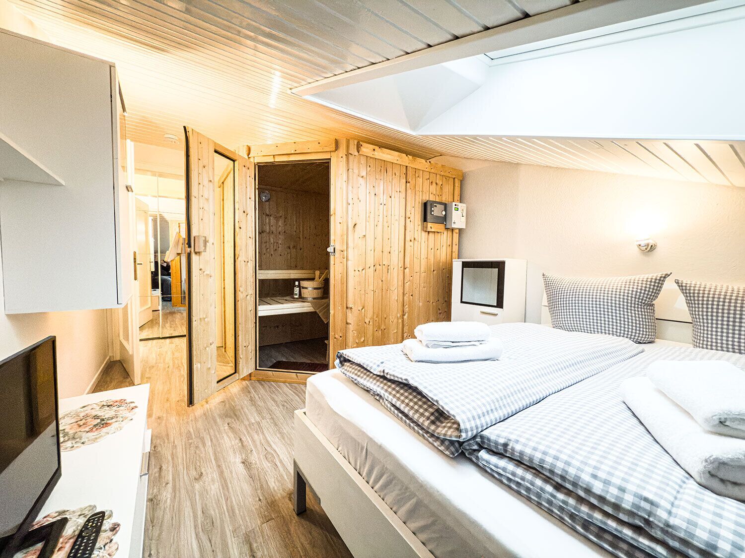 Ein Schlafzimmer mit einem Bett, einem Fernseher, einem Schreibtisch und einem Holzschrank.