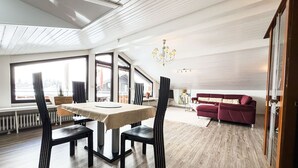 Un amplio salón con una mesa de comedor, sillas, un sofá rojo y una araña.