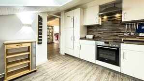 Una cocina moderna con armarios blancos, horno empotrado y tragaluz.