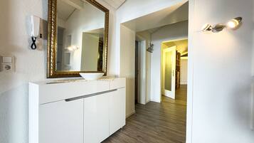 A hallway with a white vanity, a large mirror, and a light fixture.