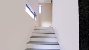 Een trap met een leuning, die uitkomt op een plateau met een klein raam.
