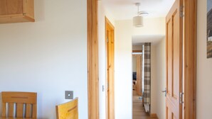 A wooden interior with a dining table and chairs, a hallway leading to another room, and a ceiling light fixture. - Ben Edra Croft by Interhome (North Skye)
