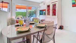 A modern dining area with a glass table, chairs, and a view of the outdoors. - Le Chaville by Interhome (Cagnes-sur-Mer)