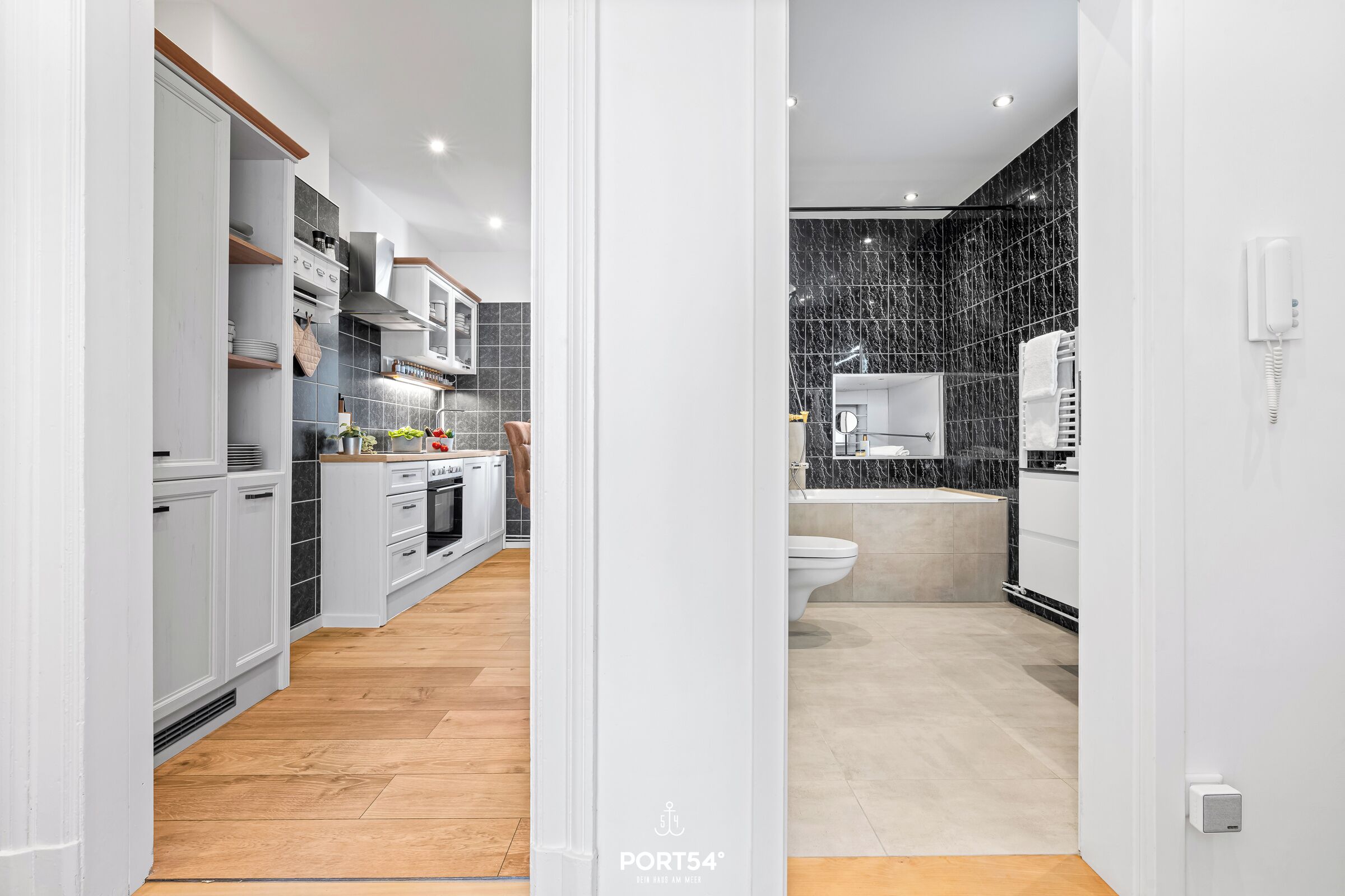 A modern kitchen with white cabinetry, a built-in oven, and a wooden floor.