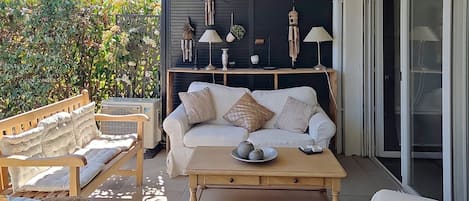 A patio with a sofa, chairs, a coffee table, and a wall-mounted light fixture.