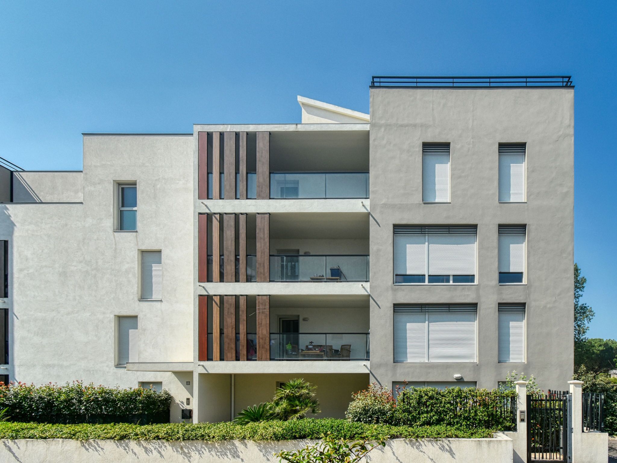 A multi-story residential building with balconies, a flat roof, and a gated entrance.