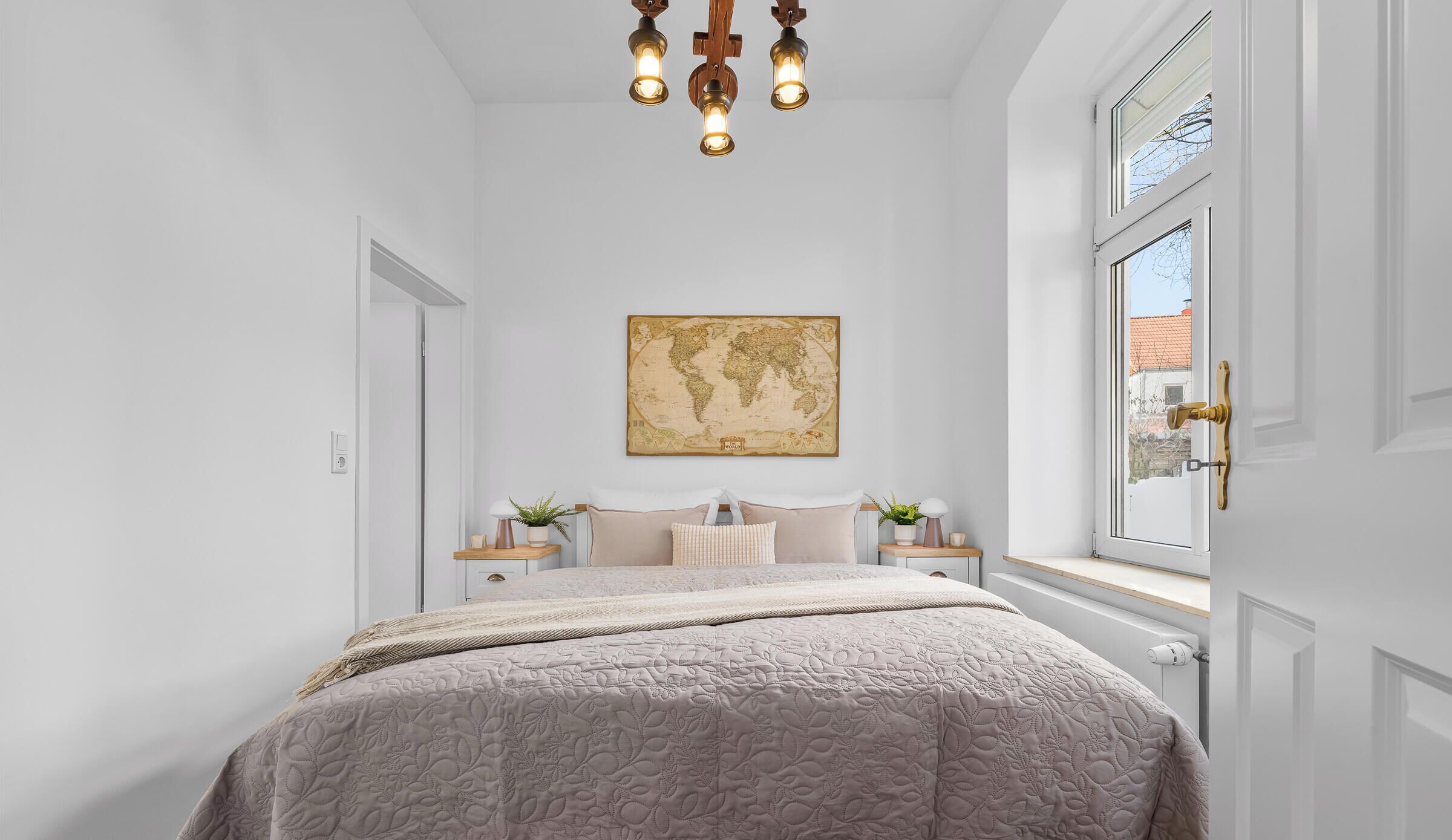 Une chambre à coucher avec un lit, une œuvre d’art représentant une carte du monde, une fenêtre et un lustre.