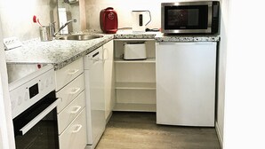 Eine kleine Küche mit weißen Schränken, einer Mikrowelle, einem Wasserkocher und einem Toaster.