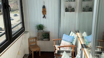 Un balcón con sillas de madera, una mesita y plantas en macetas.