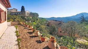 A terraced garden with potted plants, a paved walkway, and traditional buildings with tiled roofs. - L´Argentière by Interhome (Les Adrets)