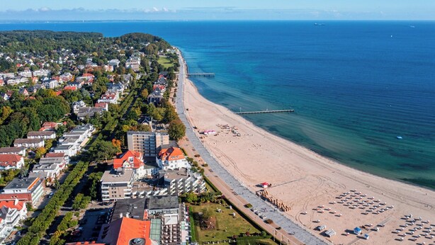 An aerial view of a coastal town with a beach, buildings, and a pier. - Ferienwohnung Sonnenstrand Travemünde: Nähe zum Sandstrand & Ostsee-Gefühl (Lübeck)