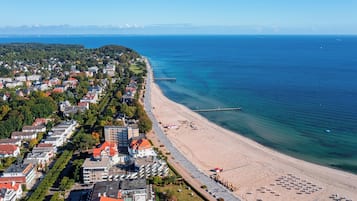 Ein Luftbild einer Küstenstadt mit Strand, Gebäuden und einem Steg.