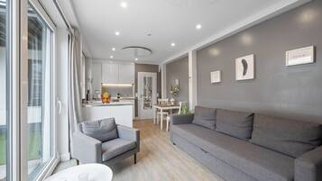 Ein modernes Wohnzimmer mit einem grauen Sofa, einem kleinen Sessel und einem Esstisch.
