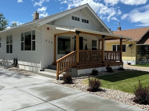 A single-story house with a covered porch, a visible garage door, and a well-maintained lawn. - Romance + Relaxation in Downtown Loveland (Loveland)