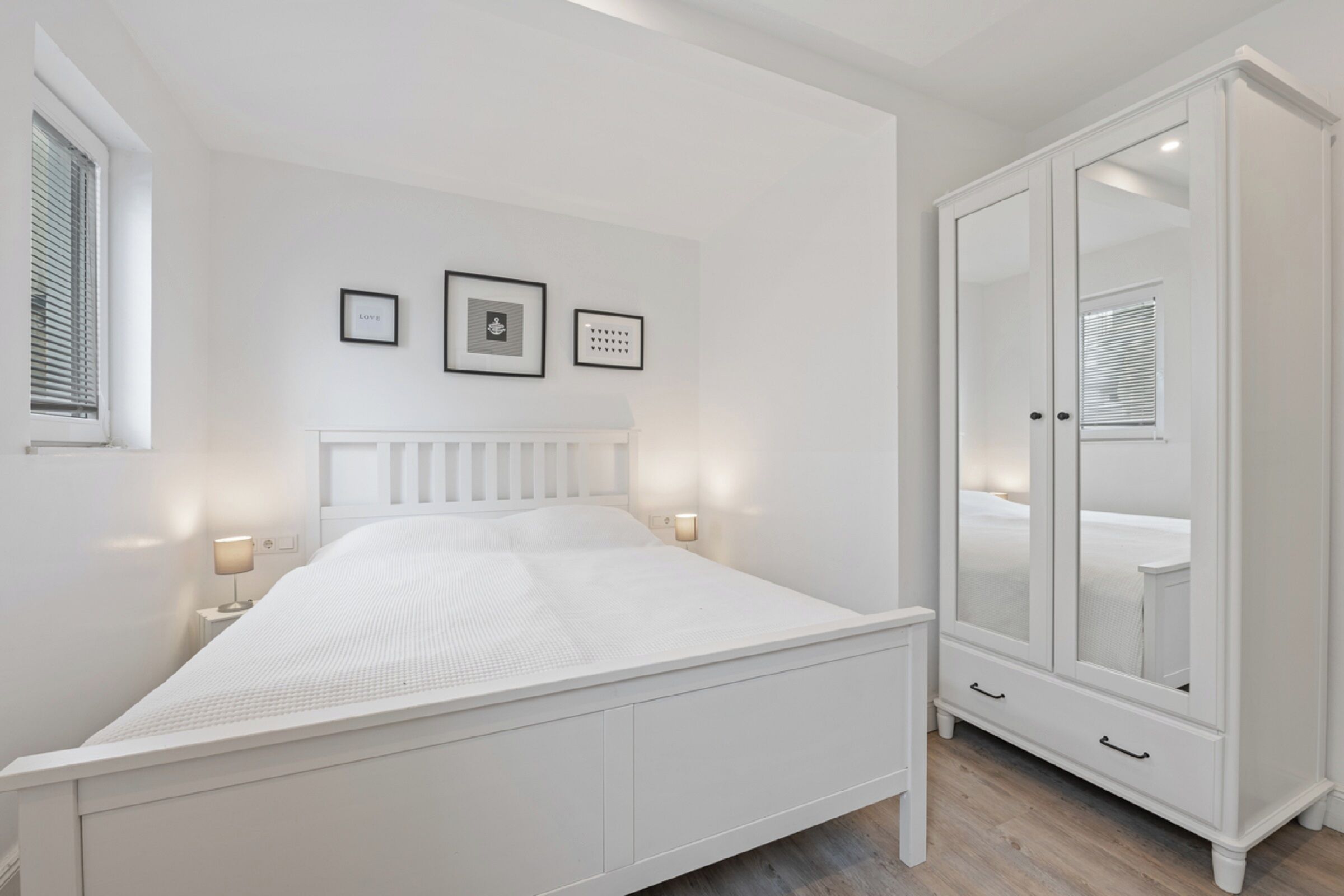 Een slaapkamer met een bed, een kledingkast en wandlampen.