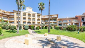 A hotel with a central courtyard, palm trees, and a building with multiple balconies. - Les Rivages des Issambres by Interhome (Les Issambres)