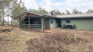 Ett envåningshus med en inglasad veranda, en skorsten och en liten sittplats utomhus.