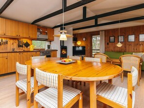Un interior de madera con una mesa redonda de comedor, sillas, un televisor y una chimenea.