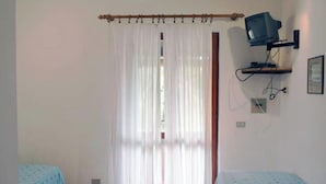 A room with two beds, a TV on a stand, and a curtain. - Casa Roberta apartment 2 (Capoliveri isola d'Elba)