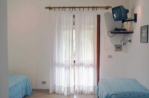 A room with two beds, a TV on a stand, and a curtain. - Casa Roberta apartment 2 (Capoliveri isola d'Elba)