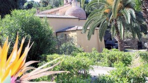 A building with a dome and a bell tower, surrounded by lush greenery and palm trees. - Casa Roberta apartment 2 (Capoliveri isola d'Elba)