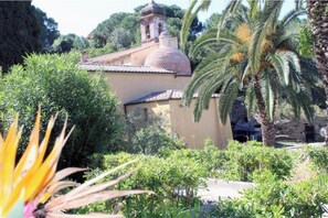 A building with a dome and a bell tower, surrounded by lush greenery and palm trees. - Casa Roberta apartment 2 (Capoliveri isola d'Elba)