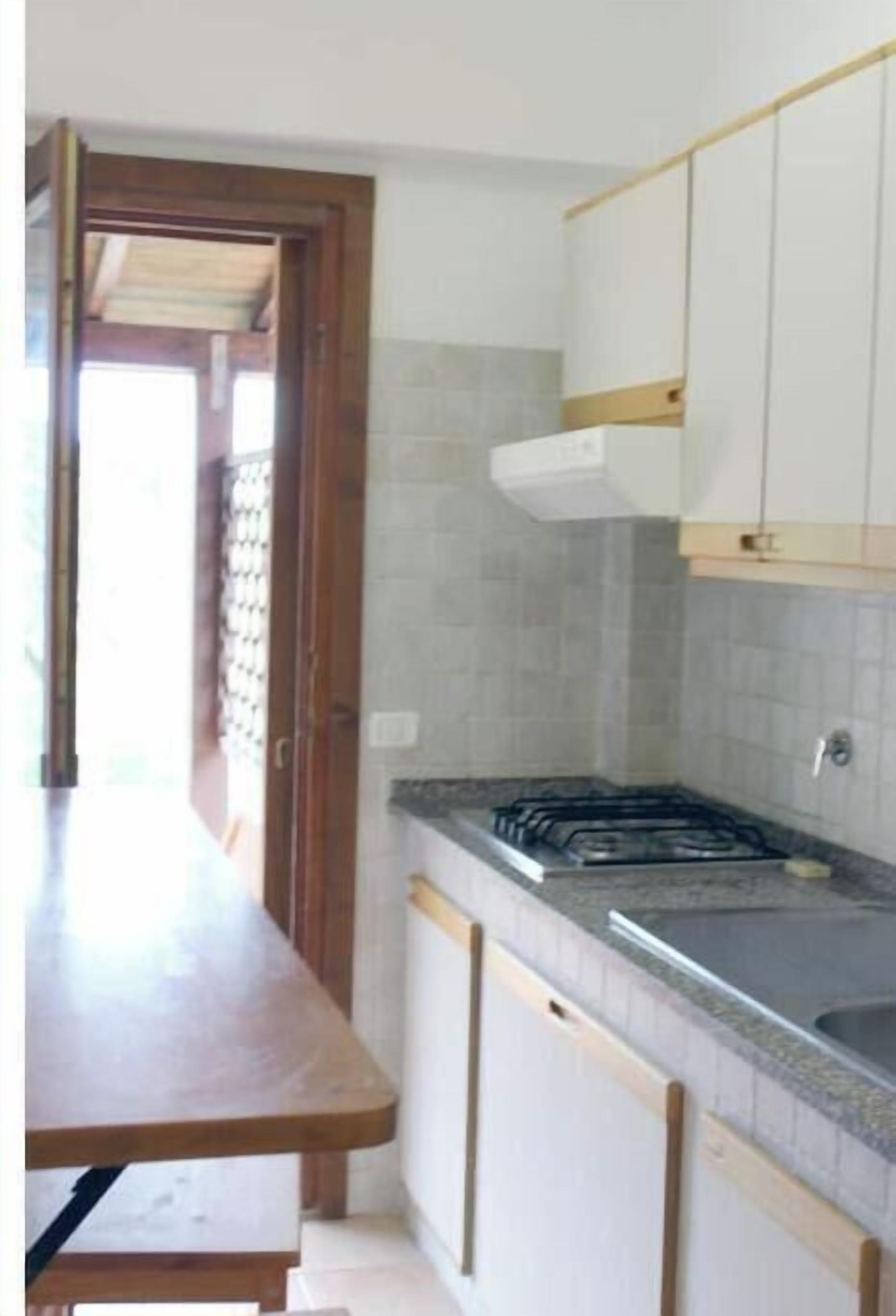 A kitchen with a countertop, sink, and cabinets.