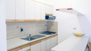 A modern kitchen with white cabinetry, a stainless steel sink, and a built-in oven. - Casa Roberta apartment 3 (Capoliveri isola d'Elba)