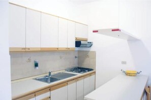 Eine moderne Küche mit weißen Schränken, einer Edelstahlspüle und einem eingebauten Backofen.