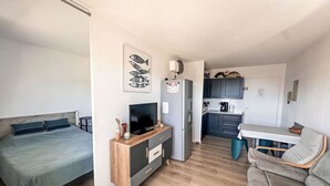 A compact living space with a bed, a TV, a kitchenette, and a dining area. - Saint James by Interhome (Le Lavandou)
