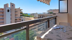 A balcony with a table and chairs, overlooking a residential area with buildings and a clear sky. - Saint James by Interhome (Le Lavandou)