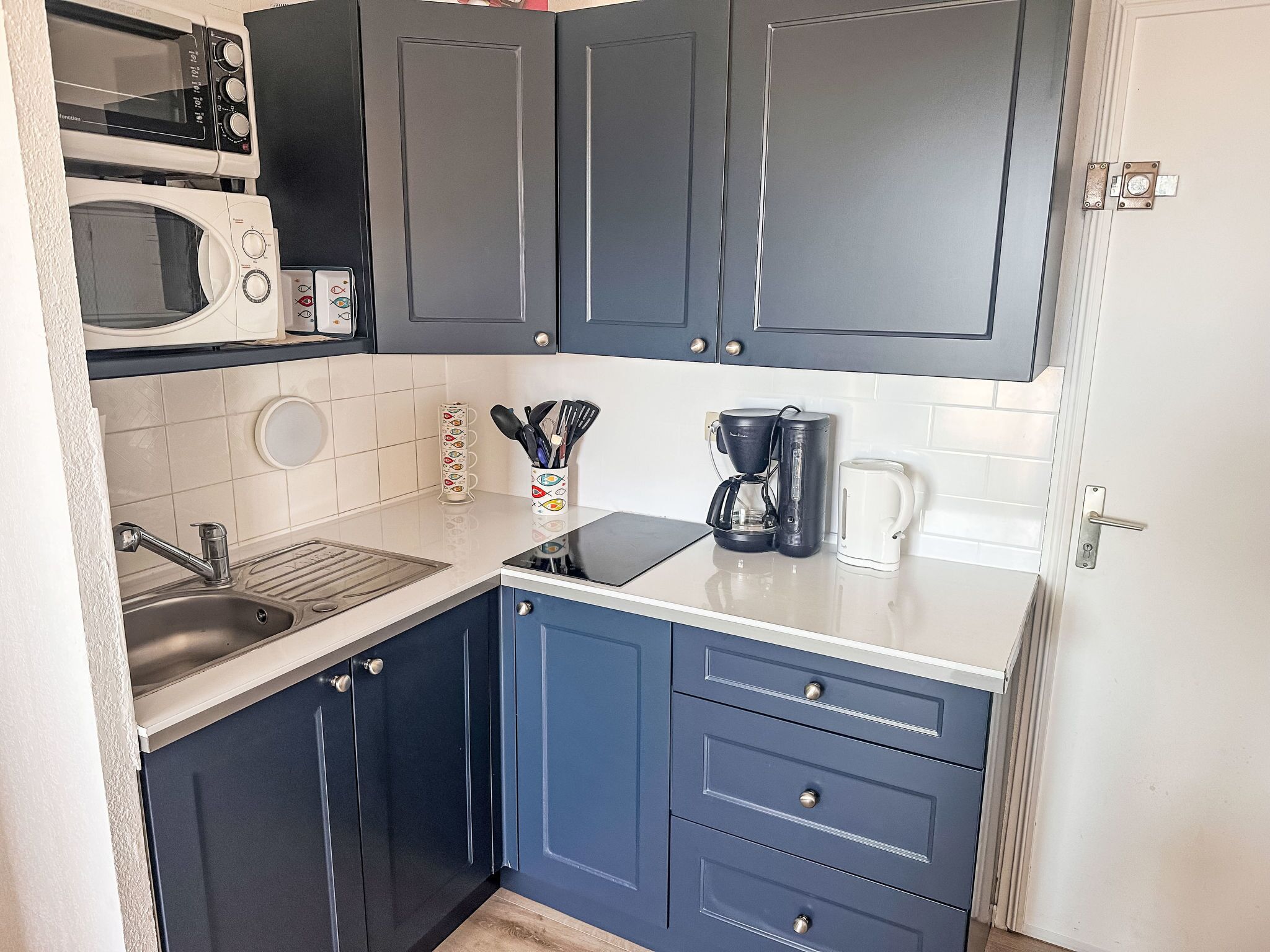 A compact kitchen with a microwave, coffee maker, and a sink.
