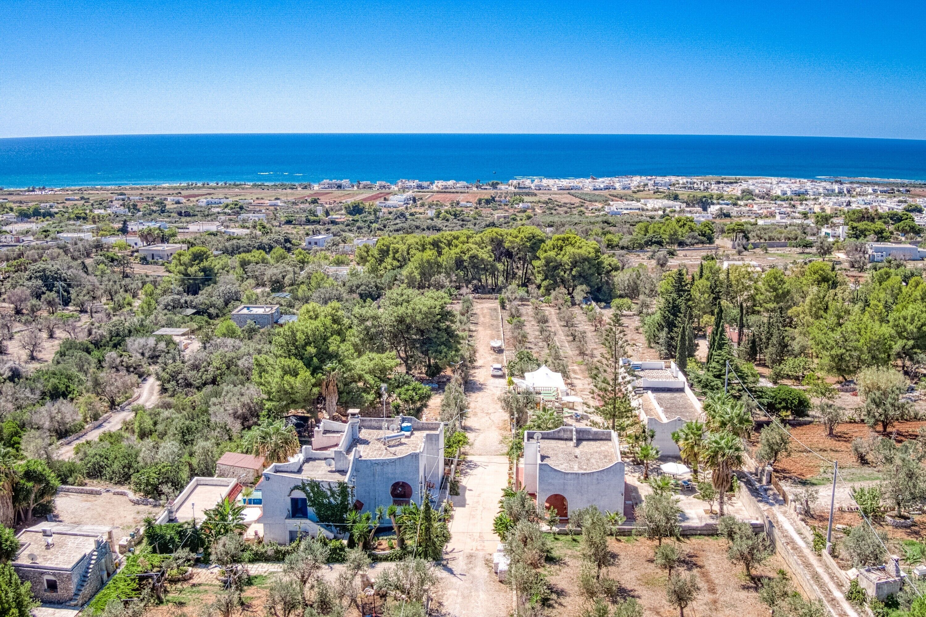 An aerial view of a coastal town with buildings, roads, and a clear blue sky.