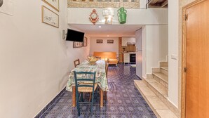 Ein Essbereich mit Tisch und Stühlen, eine Küche im Hintergrund und eine Treppe, die zu einer oberen Ebene führt.