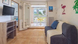 Una stanza con TV, divano, tavolo da pranzo e vista attraverso una porta in vetro.