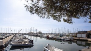 Una marina con diverse imbarcazioni ormeggiate, un molo di legno e un edificio con la scritta "Restaurant Quais Sud".