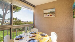 Zona pranzo con tavolo apparecchiato per quattro persone, un quadro appeso e vista sulla spiaggia dalla finestra.