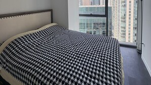 Un dormitorio con una cama grande, un ventanal con vistas a la ciudad y un respiradero en el techo.