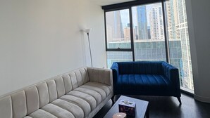 Una sala de estar moderna con un sofá color beige, un sofá azul y una pequeña mesa con una vela y una caja.