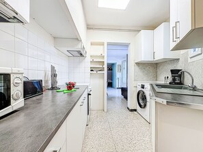 Een keuken met witte kastjes, een wasmachine en een magnetron.
