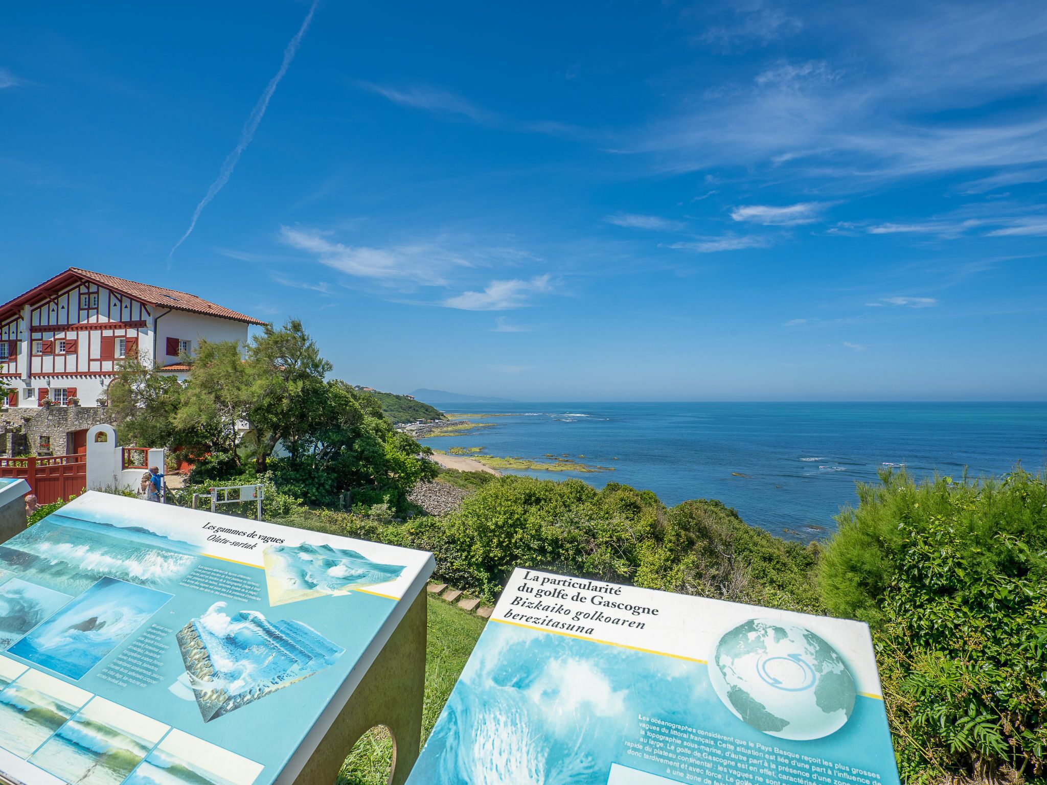 A coastal view with a house and informational signs.