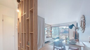 A modern living room with a dining area, wooden shelving, and a large window offering a view. - Maris Stella by Interhome (Arcachon)