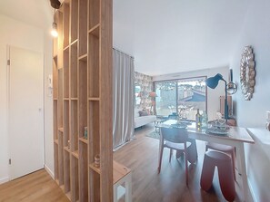 Ein modernes Wohnzimmer mit Essbereich, Holzregalen und einem großen Fenster mit Blick.