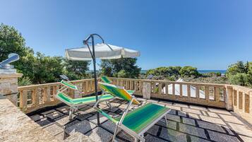 Une terrasse avec des sièges extérieurs, une pergola et une vue sur la mer.