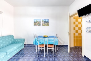 Ein Essbereich mit Tisch und Stühlen, einer Couch und zwei Bildern an der Wand.