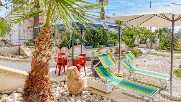 A patio area with lounge chairs, a palm tree, and a covered seating area. - Mono Glicine - Charming Studio on the Salento Coast (Salve)