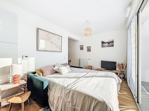 A modern bedroom with a bed, a desk, a chair, a television, and artwork on the walls. - Ar Marine by Interhome (Quiberon)
