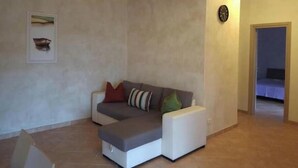 Un salon avec un canapé, une horloge et un tableau encadré accroché au mur.